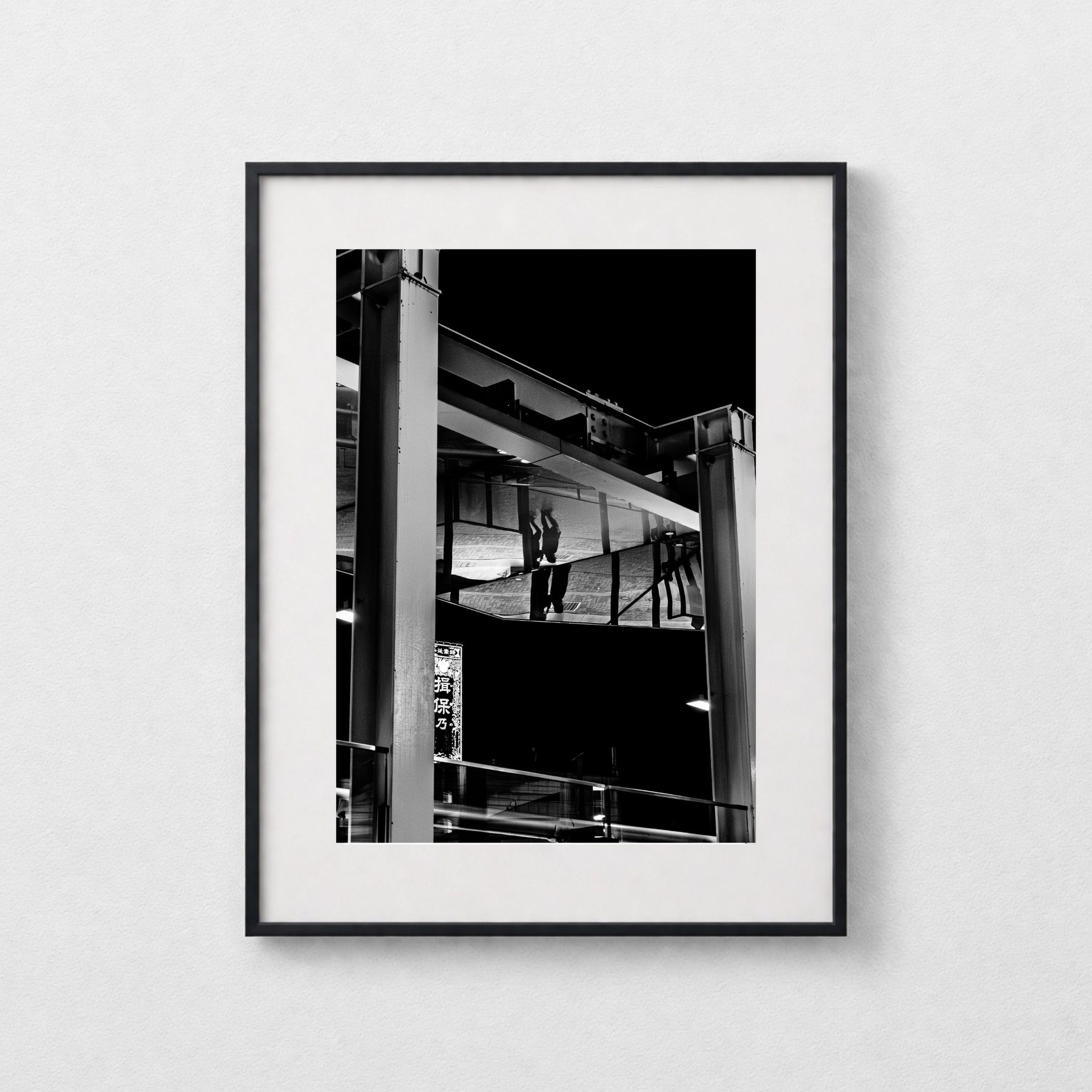 Reflection shown in a black frame against a grey wall.